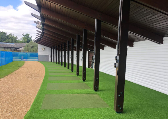 Metro New York Covered outdoor tee line with light green synthetic grass boxes inside a dark green synthetic grass strip